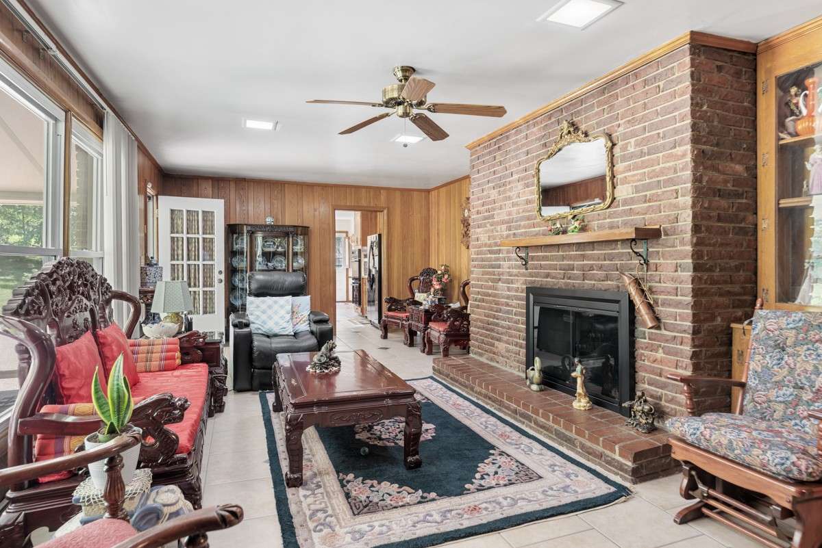 Spacious great room off the kitchen with a cozy fireplace, large windows, and easy access to the pool and covered back patio—ideal for relaxing or entertaining.