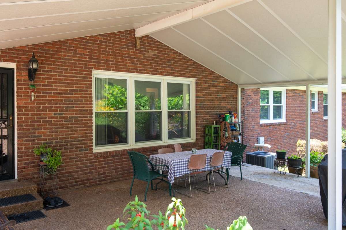Backyard oasis featuring a covered patio, lush landscaping, and a seamless walkway leading to the pool—perfect for relaxing or entertaining outdoors.