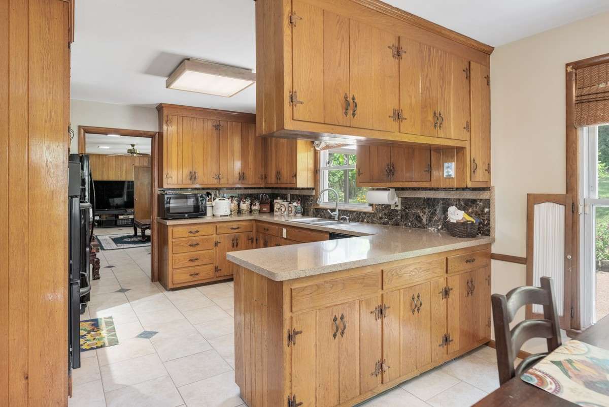 Spacious kitchen with abundant cabinetry, large countertops, and a window offering views of the backyard and pool—perfect for meal prep with a relaxing outlook.