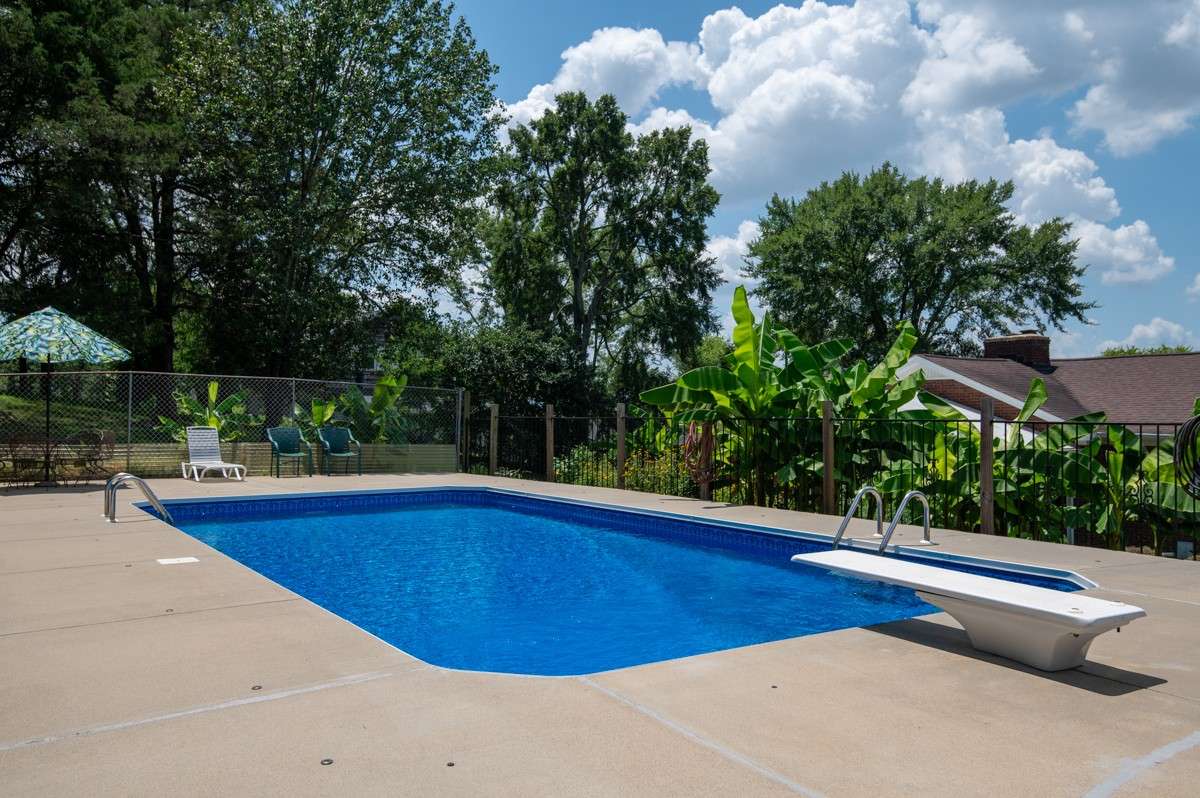 Enjoy a 33 x 16 inground pool with a diving board, surrounded by privacy fencing and lush landscaping—perfect for summer fun and relaxation.