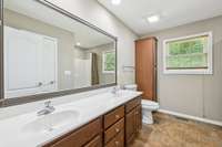 Primary bath featuring double sinks, tile flooring, and a convenient linen closet.