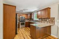 Kitchen featuring granite countertops, tile backsplash, and plenty of workspace.