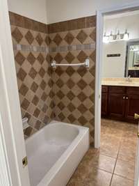 Two separate bathrooms with toilets/vanities, each attached to shared tub-shower combo area.