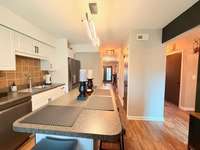 Kitchen has backsplash with quartz countertops; bar seating; flowing into the Den/Living Room areas