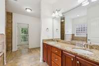 Primary bath room.  Granite countertops with double vanities.  Electric radiant floor heating installed under the tile. Bathroom includes a urinal as well as a standard toilet.  Large linen closet also.