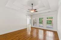 Living Room with large windows looking over the covered back porch and concrete extended patio.  Coffered ceilings and extensive trim.