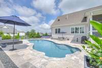 Travertine deck surrounds the pool and hot tub.