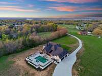 True oasis! Gunite salt-water sports pool and spa with tanning ledge. Outdoor Kitchen with Napoleon and True appliances, gas fireplace, fire pit, and a designated outdoor bathroom!  
*Picture was taken back in March, yard has been hydroseeded.