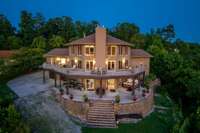 This house was made to impress!  This view perfectly showcases the multiple expansive outdoor living and entertainment areas and the floor to ceiling windows that flood the home with light and views of the lake.