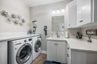 Laundry room/half bath with plenty of cabinetry for storage and quart countertops.