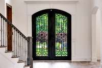 Grand entryway showcases double wrought iron doors, elegant wood floors, and a sweeping staircase—setting the tone for timeless luxury throughout the home.