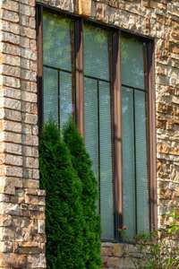 Expansive windows framed in bronze-toned trim allow natural light to pour in while enhancing the rich stone facade with elegant contrast.