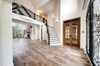 Stunning new hardwood-style flooring flows throughout this expansive open-concept layout, seamlessly connecting the grand foyer, elegant staircase, and two-story living area.