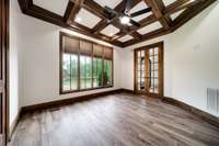 Stunning main-level office with coffered ceiling, French doors, picture window, custom blinds, and luxury vinyl plank floors—freshly painted in designer tones.