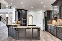 Spacious gourmet kitchen with freshly painted solid wood cabinetry, granite countertops, and a center prep island—open to the grand living space and foyer for seamless entertaining.