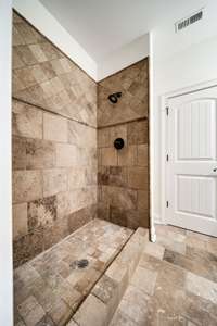 Fully tiled shower and flooring in guest bathroom.