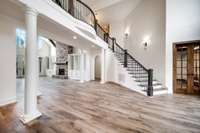 Dramatic two-story great room with freshly painted designer colors throughout. Graceful columns frame the space, offering a seamless flow into the main living areas and formal office beyond.