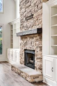 Rustic elegance shines through with a floor-to-ceiling stone fireplace, complete with a weathered wood beam mantel and custom built-ins.