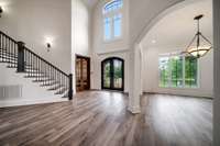 Step into a soaring two-story foyer adorned with dramatic iron doors, expansive windows, and brand-new wide-plank flooring that seamlessly continues into the formal dining area.