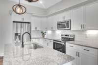 This kitchen is stunning with a large island, granite counter tops, tile back splash and under cabinet lighting.