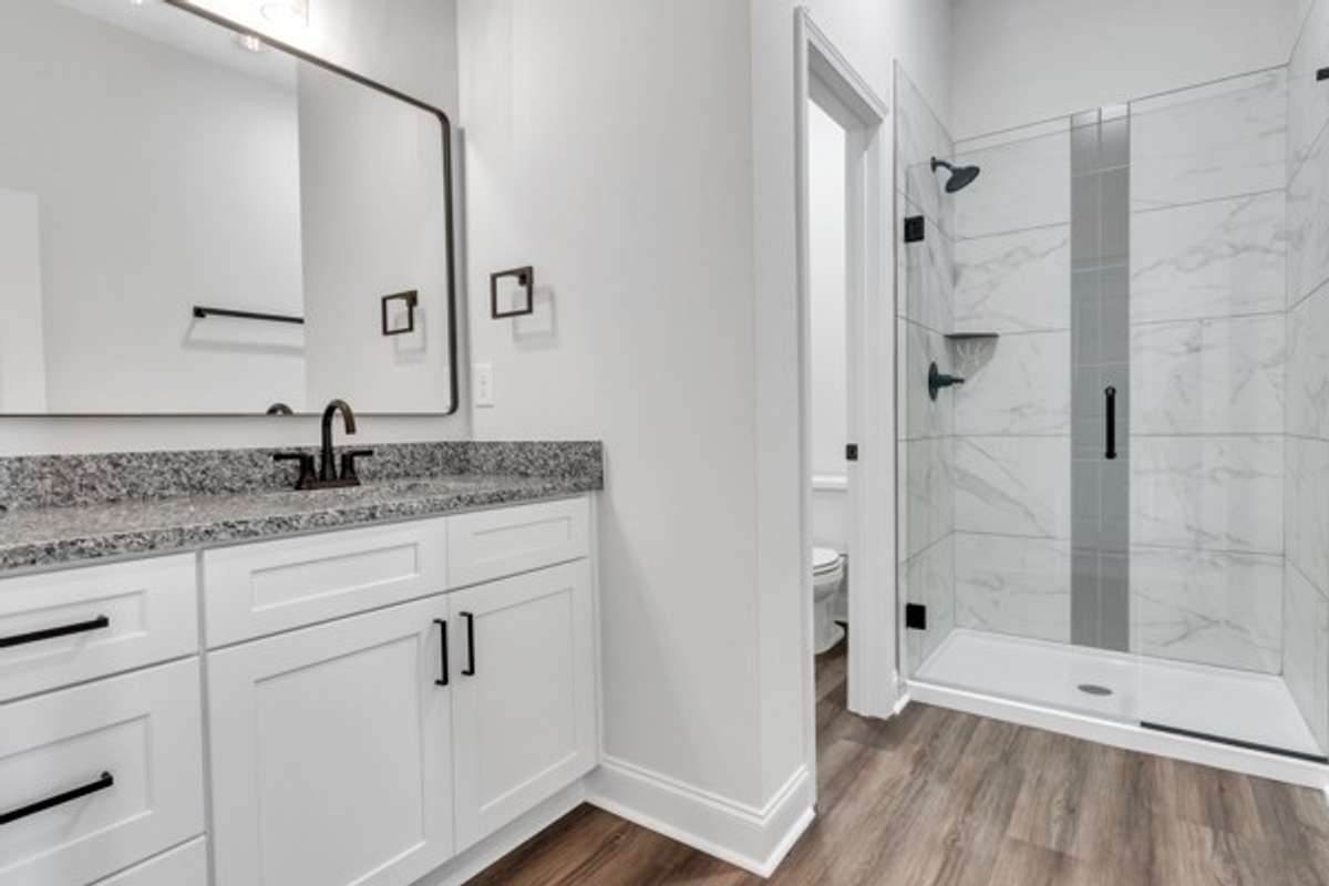 Spacious primary bath with granite, elegant tile and modern fixtures, decor & lighting. With the 10 ft ceilings and glass shower it has a true spa feeling!