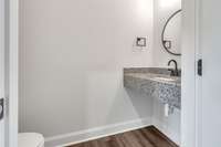 1st floor half bath featuring granite, modern lighting, fixtures & decor.