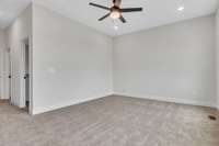 A shot back toward the entry of primary bedroom featuring beautiful recessed lighting and a modern fan and light.