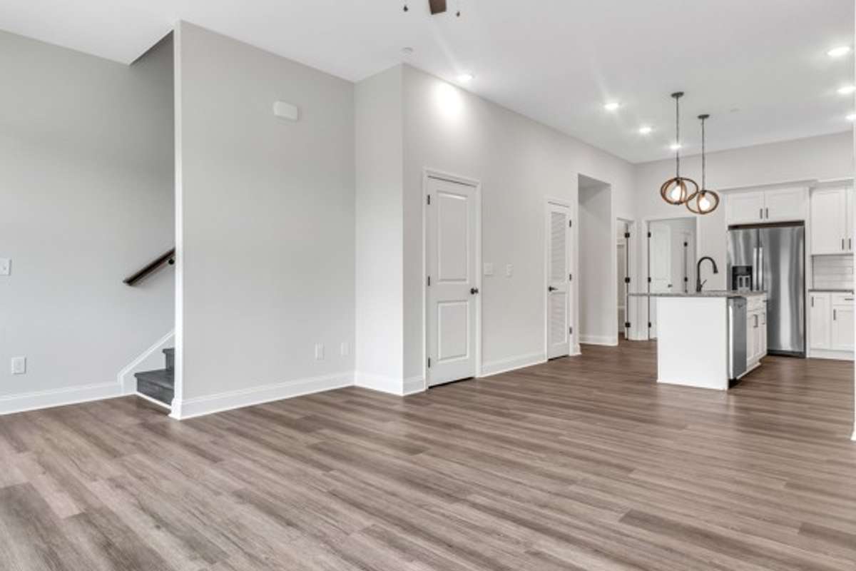 A look back from the front part of the living space toward the kitchen with the guest bedroom behind and to the left entry to stairs up to the second and third bedroom and laundry room.