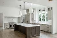 A culinary showpiece—this kitchen boasts JennAir appliances, a stunning quartz and wood island, touchless fixtures, and custom Wynnbrooke and Koch cabinetry with an integrated refrigerator. The trio of pendant lights adds warmth and sophistication.