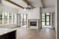 Flooded with natural light, the living room is a showstopper—featuring an abundance of windows, elegant French doors flanking a statement fireplace, and a stunning chandelier that adds timeless sophistication to this inviting gathering space.