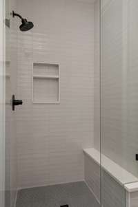 Sleek and timeless, this walk-in shower features crisp white tile, built-in storage niches, and premium fixtures.