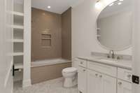 A stylish and functional bath featuring a sleek vanity with quartz countertops and a bathtub-shower combo.