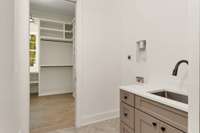 The lower laundry room is located just outside the primary closet and comes with custom cabinetry, a deep sink with touchless fixture, and smart prewiring.