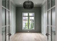 Muted green walls, a sexy black chandelier, and custom trim create a timeless entrance to the study.