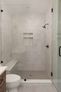 Experience spa-like luxury in this walk-in shower, complete with elegant tilework, built-in storage niches, and a convenient seating area for added comfort and relaxation.