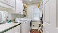 Large very functional laundry room with sink and an abundance of storage cabinets.