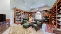 This expansive library showcases custom-built cherry bookcases with a rolling ladder and rich cherry wainscoting, creating a warm and distinguished literary retreat.