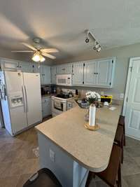 Track lighting over the breakfast bar and a ceiling fan for when it gets too hot in the kitchen!
