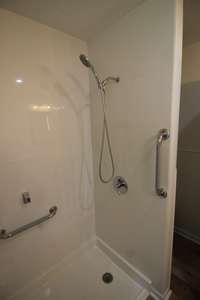 Walk in shower with sides going all the way to the ceiling for wall protection and easy cleaning.