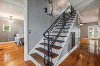 Wooden Staircase leading to the upper level with decorative Iron Railing