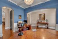 Formal Dining Room currently being used as a home office features finished wood floors, beautiful lighting and coffered ceiling.