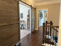 Landing off the Staircase on the second floor.  The staircase features wood treads and iron spindles.  The landing features finished wood floors.