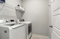 The utility room is conveniently located near the primary suite, and features a long storage shelf, and a door to keep everything tucked away out of sight!