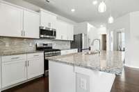 Sleek and functional white kitchen boasting generous counter space and ample storage - ideal for cooking, hosting, and everyday living.