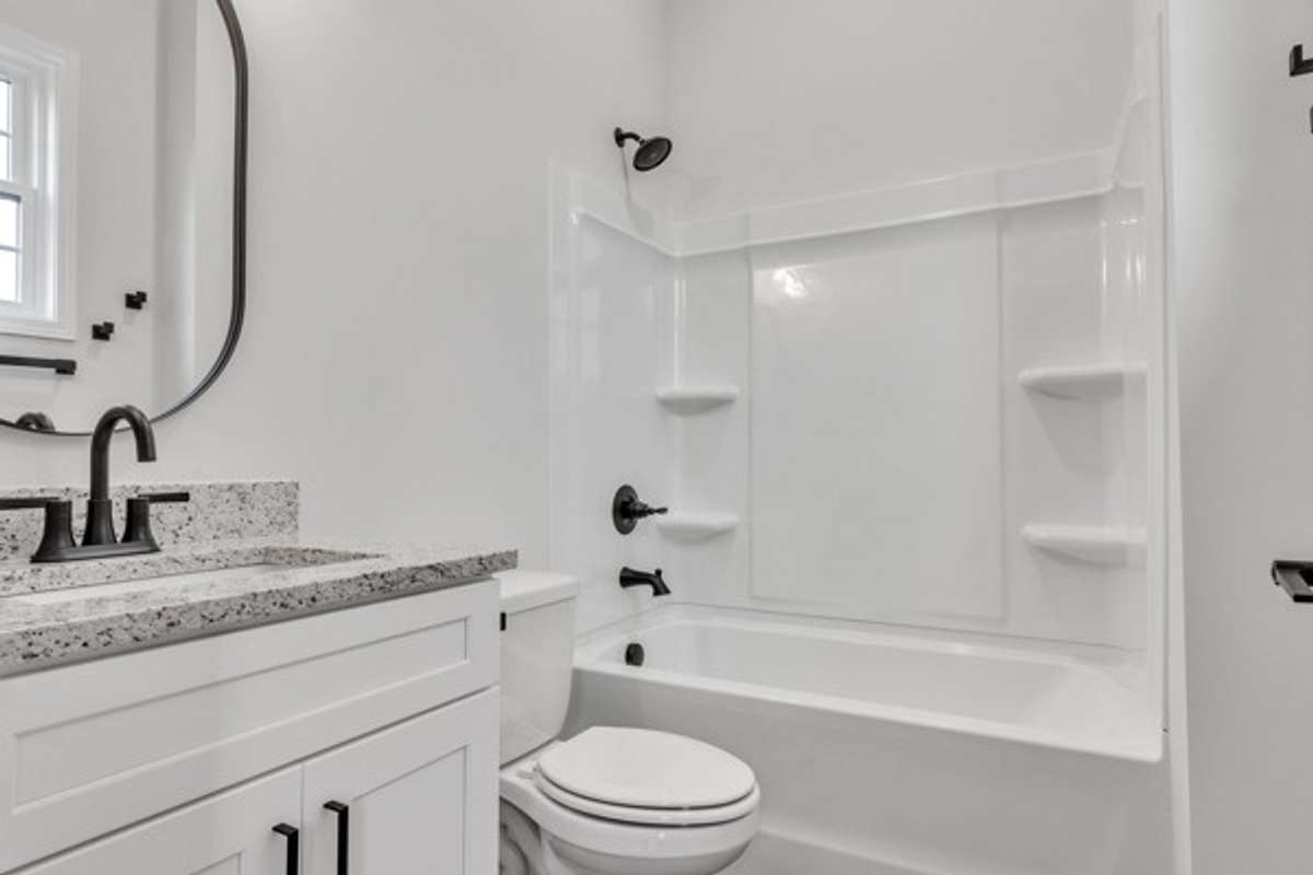 Private bath for 2nd guest bedroom with 10 ft ceilings, granite & modern decor and fixtures all highlighted by a window for natural lighting.