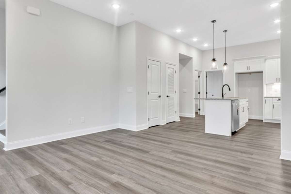 A look back from the front part of the living space toward the kitchen with the guest bedroom behind and to the left entry to stairs up to the second and third bedroom and laundry room.