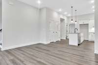 A look back from the front part of the living space toward the kitchen with the guest bedroom behind and to the left entry to stairs up to the second and third bedroom and laundry room.