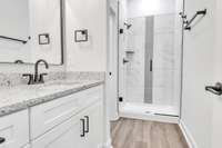 Spacious primary bath with granite, elegant tile and modern fixtures, decor & lighting. With the 10 ft ceilings and glass shower it has a true spa feeling!