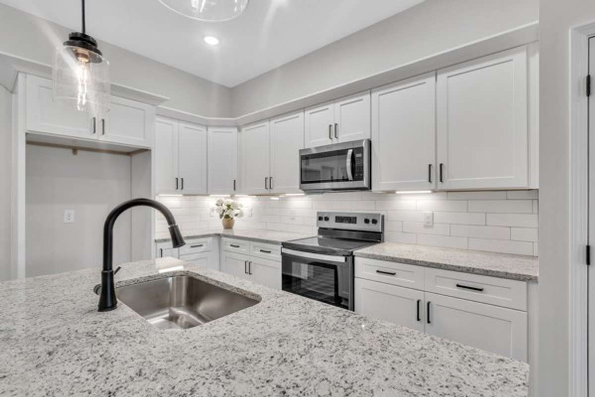 This kitchen is stunning with a large island, granite counter tops, tile back splash and under cabinet lighting.
