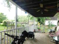 Porch has a metal roof, appears to be in good condition as does the wooden floor and rails